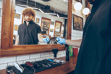 Image showing Male barber at the barbershop wearing gloves preparing working p