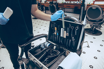 Image showing Male barber at the barbershop wearing gloves preparing working place for client