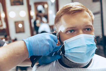 Image showing Man getting hair cut at the barbershop wearing mask during coronavirus pandemic