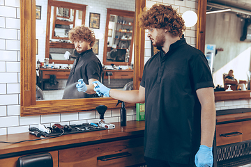 Image showing Male barber at the barbershop wearing gloves preparing working p