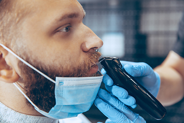 Image showing Man getting hair cut at the barbershop wearing mask during coronavirus pandemic