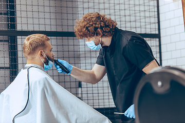 Image showing Man getting hair cut at the barbershop wearing mask during coronavirus pandemic