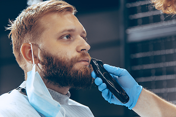 Image showing Man getting hair cut at the barbershop wearing mask during coronavirus pandemic