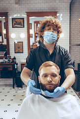 Image showing Man getting hair cut at the barbershop wearing mask during coronavirus pandemic