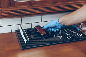 Image showing Male barber at the barbershop wearing gloves preparing working place for client