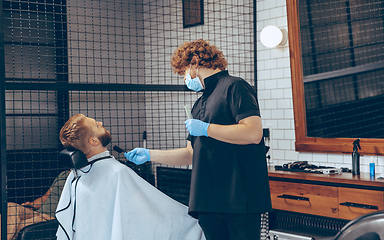 Image showing Man getting hair cut at the barbershop wearing mask during coronavirus pandemic