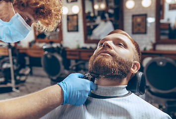 Image showing Man getting hair cut at the barbershop wearing mask during coronavirus pandemic