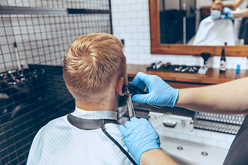 Image showing Man getting hair cut at the barbershop wearing mask during coronavirus pandemic