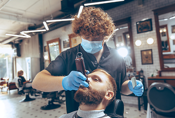 Image showing Man getting hair cut at the barbershop wearing mask during coronavirus pandemic