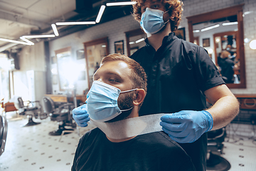 Image showing Man getting hair cut at the barbershop wearing mask during coron