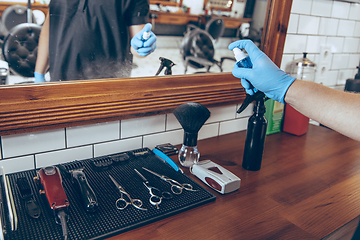 Image showing Male barber at the barbershop wearing gloves preparing working p