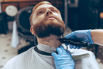 Image showing Man getting hair cut at the barbershop wearing mask during coronavirus pandemic