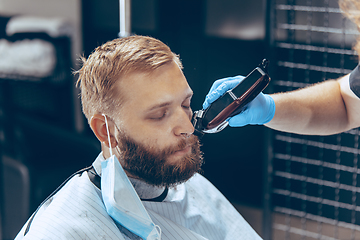 Image showing Man getting hair cut at the barbershop wearing mask during coronavirus pandemic