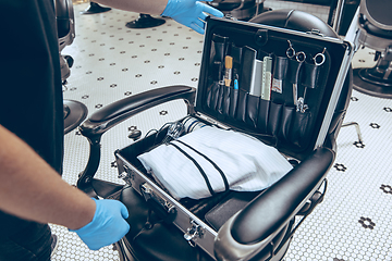 Image showing Male barber at the barbershop wearing gloves preparing working place for client