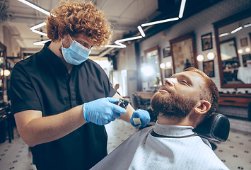 Image showing Man getting hair cut at the barbershop wearing mask during coronavirus pandemic