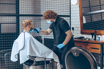 Image showing Man getting hair cut at the barbershop wearing mask during coronavirus pandemic