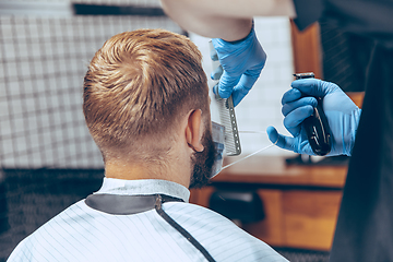 Image showing Man getting hair cut at the barbershop wearing mask during coronavirus pandemic