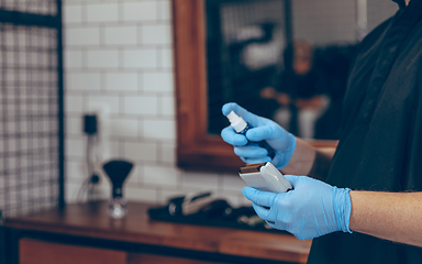 Image showing Male barber at the barbershop wearing gloves preparing working place for client