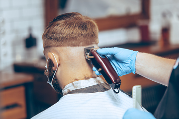 Image showing Man getting hair cut at the barbershop wearing mask during coronavirus pandemic