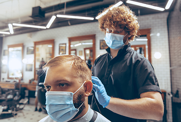 Image showing Man getting hair cut at the barbershop wearing mask during coronavirus pandemic