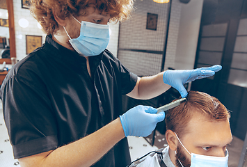 Image showing Man getting hair cut at the barbershop wearing mask during coronavirus pandemic