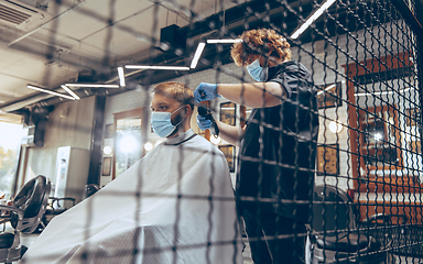 Image showing Man getting hair cut at the barbershop wearing mask during coronavirus pandemic