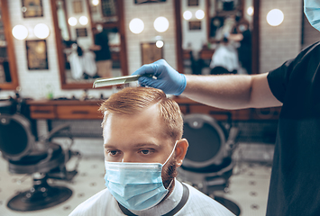 Image showing Man getting hair cut at the barbershop wearing mask during coronavirus pandemic
