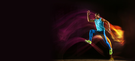 Image showing Professional male runner training isolated on black studio background in mixed light
