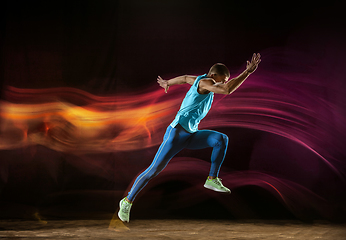 Image showing Professional male runner training isolated on black studio background in mixed light