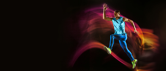 Image showing Professional male runner training isolated on black studio background in mixed light