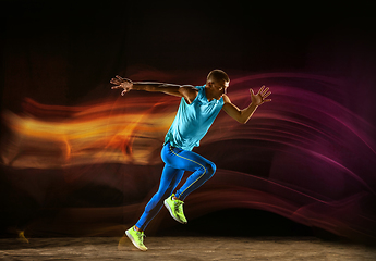 Image showing Professional male runner training isolated on black studio background in mixed light