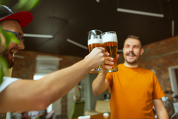 Image showing Young group of friends drinking beer, having fun, laughting and celebrating together. Close up clinking beer bottles