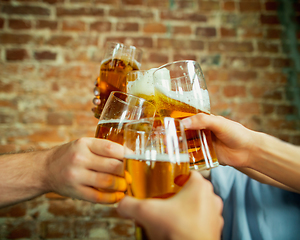 Image showing Young group of friends drinking beer, having fun, laughting and celebrating together. Close up clinking beer glasses