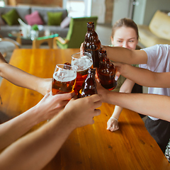 Image showing Young group of friends drinking beer, having fun, laughting and celebrating together. Close up clinking beer glasses