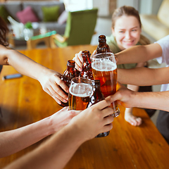 Image showing Young group of friends drinking beer, having fun, laughting and celebrating together. Close up clinking beer glasses