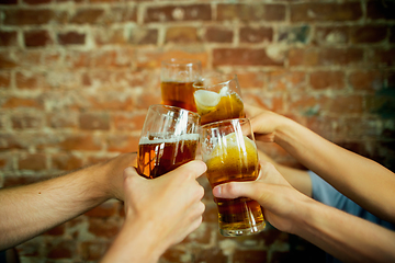 Image showing Young group of friends drinking beer, having fun, laughting and celebrating together. Close up clinking beer glasses