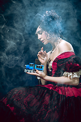 Image showing Young woman as Anna Karenina on dark blue background. Retro style, comparison of eras concept.