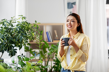 Image showing happy smiling asian woman drinking coffee at home