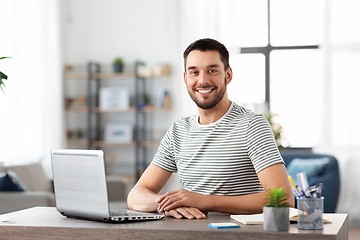 Image showing happy man with laptop working at home office