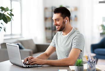 Image showing man with laptop and earphones at home office