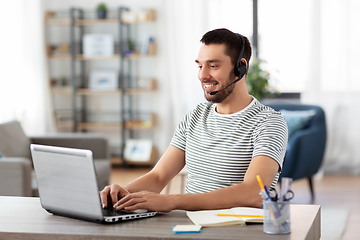 Image showing man with headset and laptop working at home