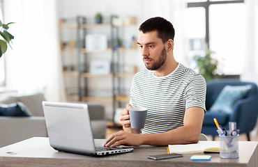 Image showing man with laptop drinking coffee at home office