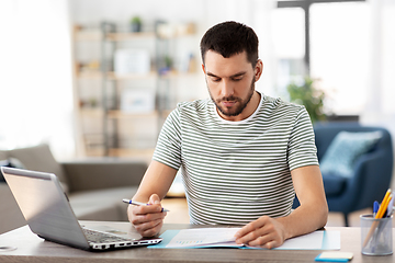 Image showing man with papers and laptop working at home office