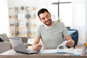 Image showing man with papers and laptop working at home office