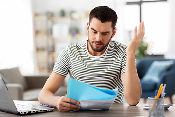 Image showing man with papers and laptop working at home office