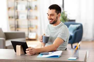 Image showing man with tablet pc drinking coffee at home office