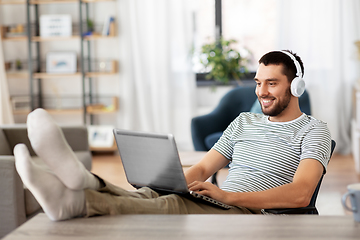 Image showing happy man with laptop and headphones at home