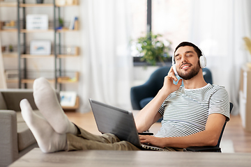 Image showing happy man with laptop and headphones at home
