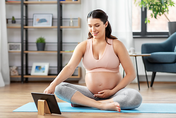 Image showing pregnant woman with tablet pc doing sports at home