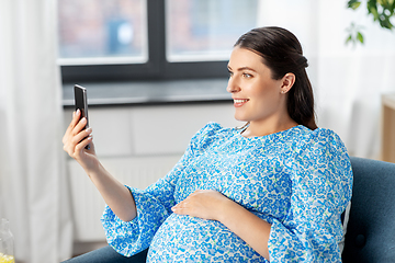 Image showing happy pregnant woman with smartphone at home